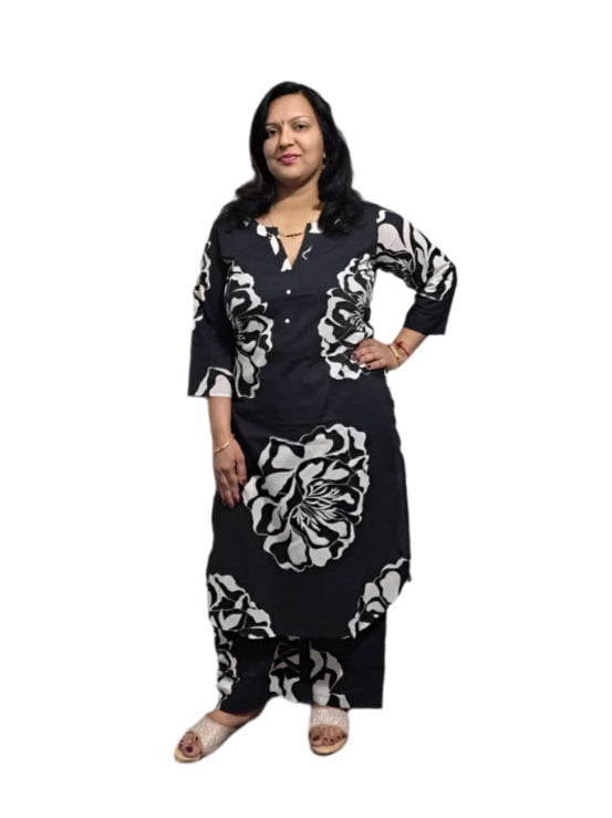 Woman in a black and white patterned outfit standing in front of an elevator.
