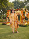 Woman in a yellow traditional outfit standing in a modern building interior.