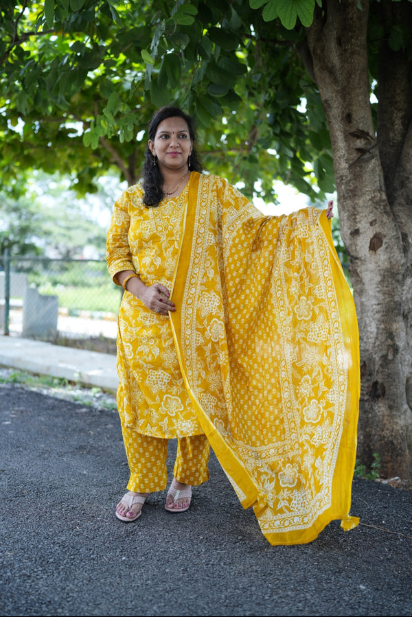 Woman in a yellow traditional outfit standing outdoors near a tree