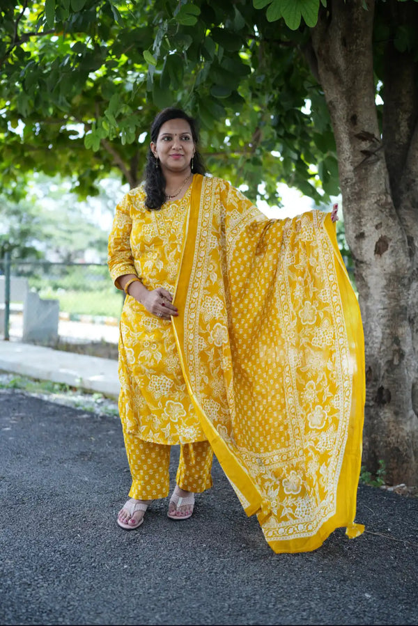 Woman in a yellow traditional outfit standing outdoors near a tree