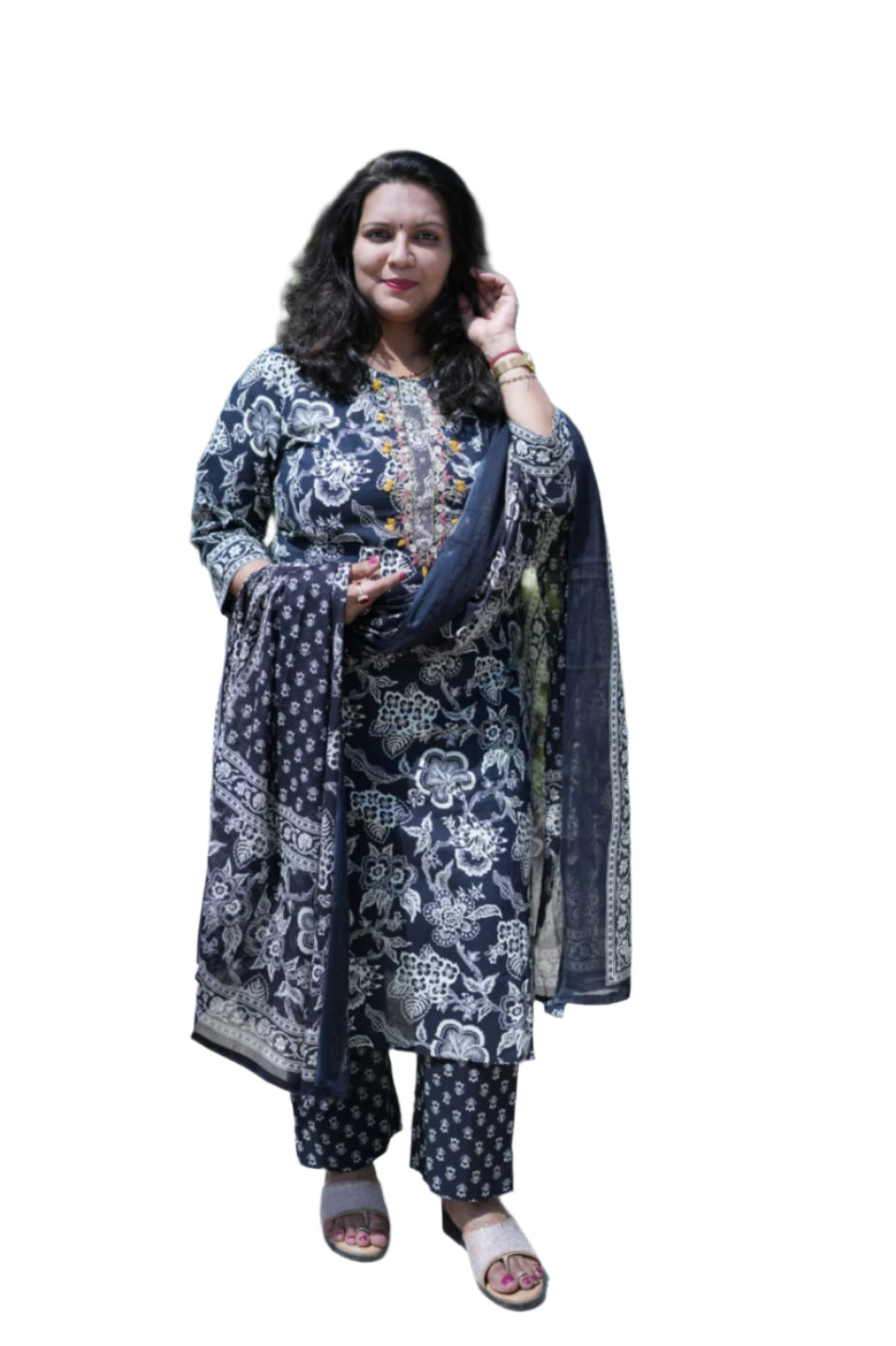 Woman in a floral outfit standing outdoors with greenery in the background
