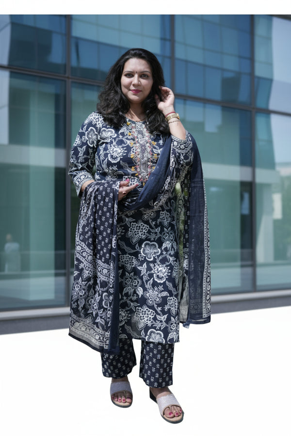 Woman in a floral outfit standing outdoors with greenery in the background