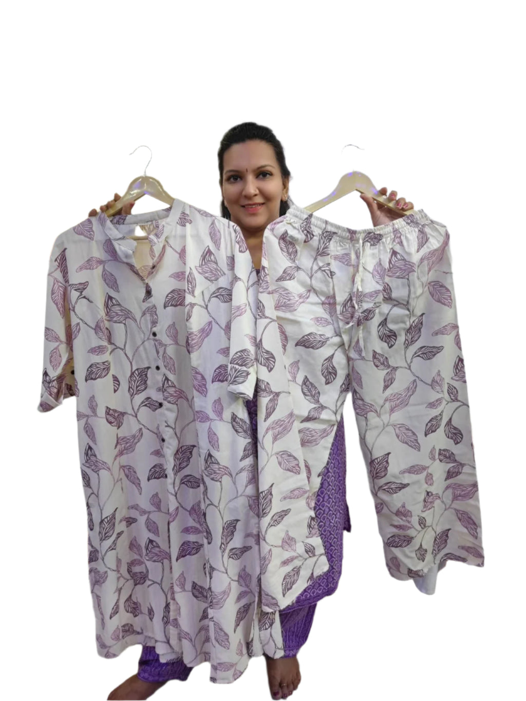 Woman holding up a matching set of pajama top and pants with purple leaf pattern.