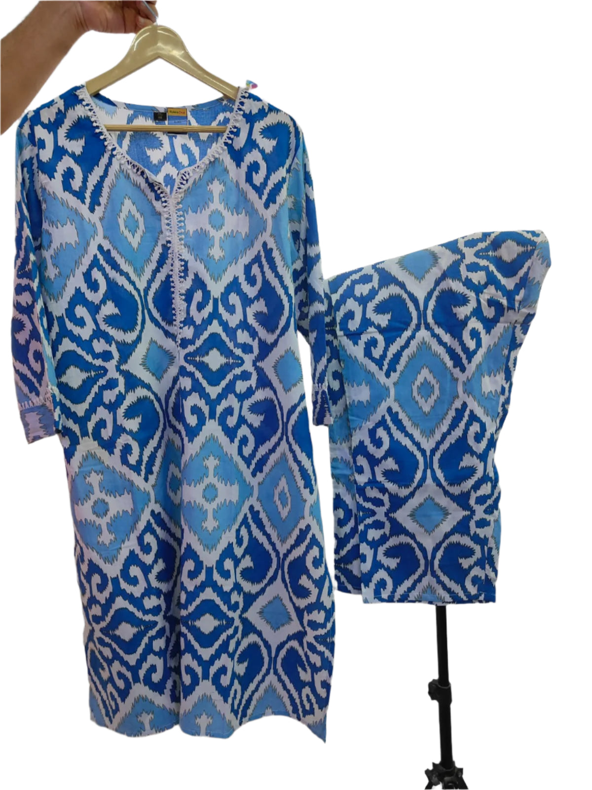 Blue and white patterned dress on a hanger with a matching pillow against a white background