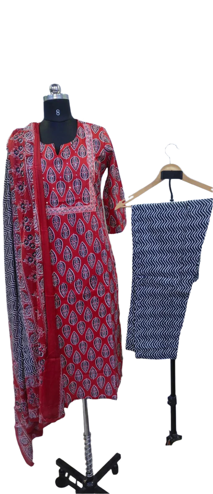 Red patterned dress with a black and white skirt on a mannequin and hanger against a white background.