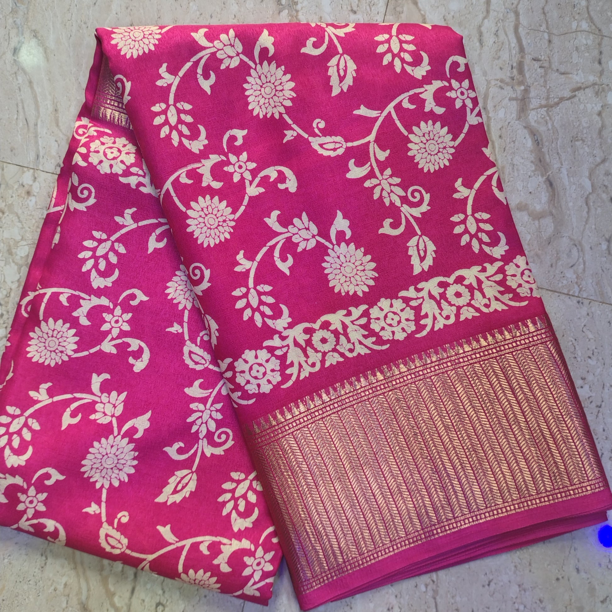 Pink saree with white floral patterns on a textured surface