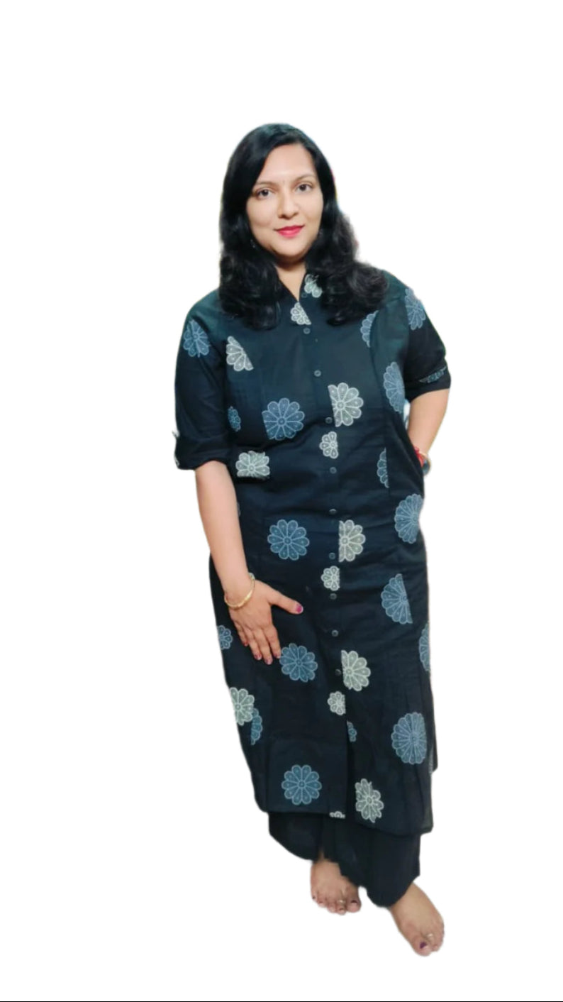 Woman in a black outfit with blue patterns standing in a clothing store.