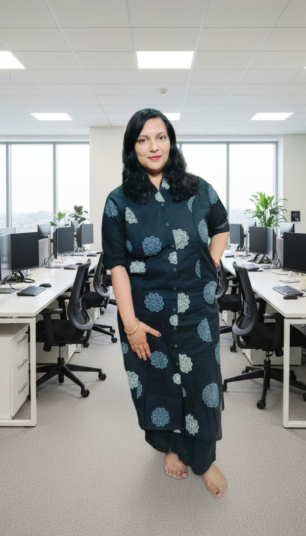 Woman in a black outfit with blue patterns standing in a clothing store.